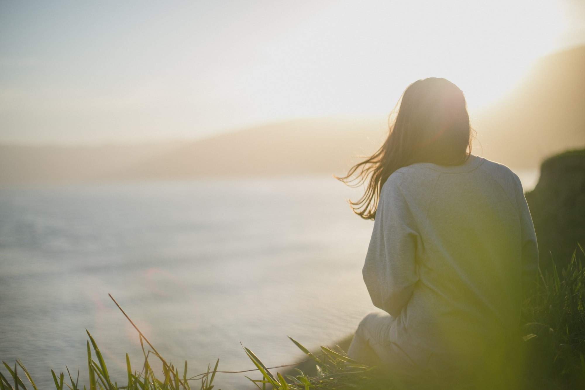 A person on the shore looking at the water in front of them. Peaceful scene.